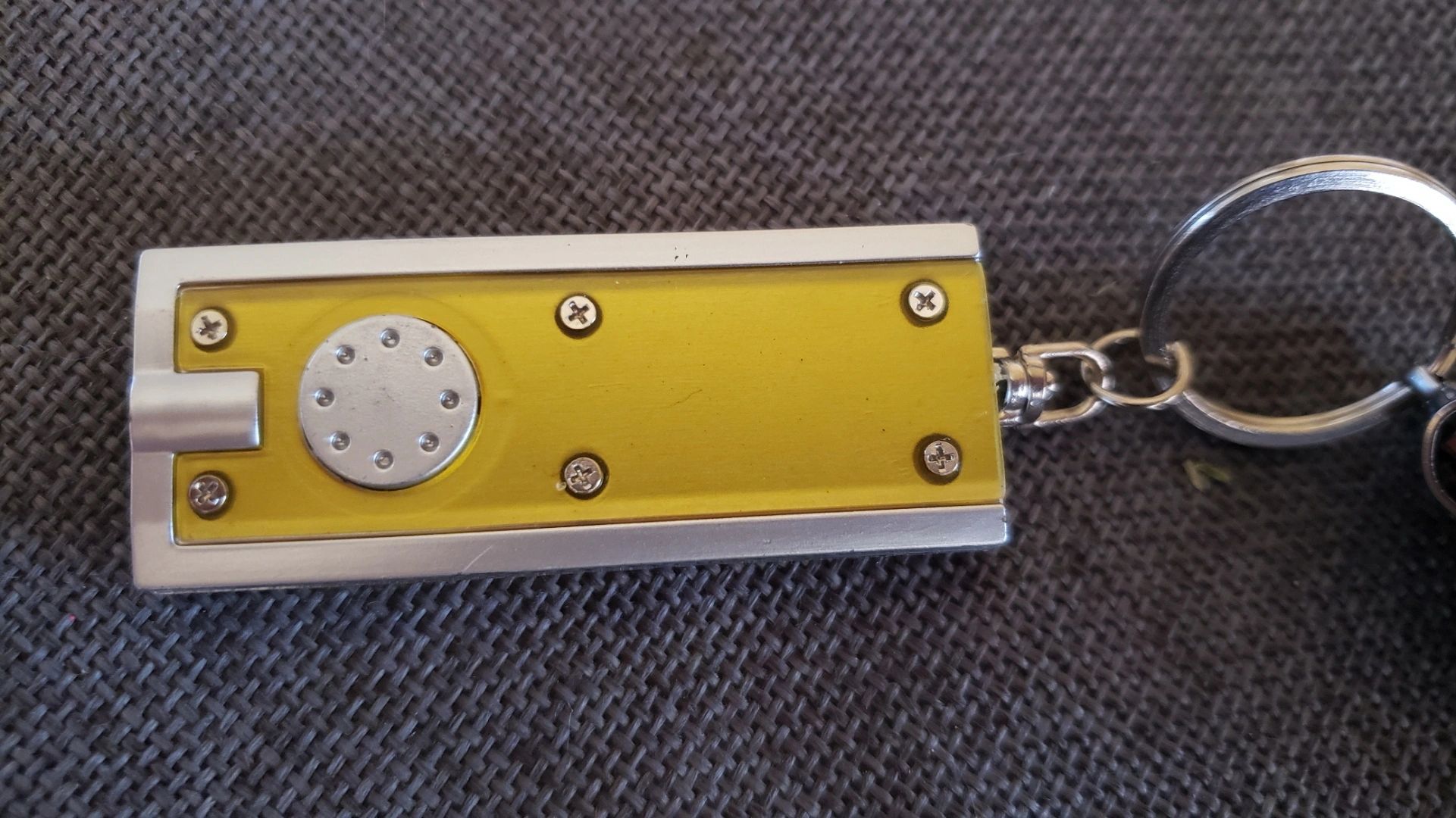 Yellow flashlight keychain on fabric surface