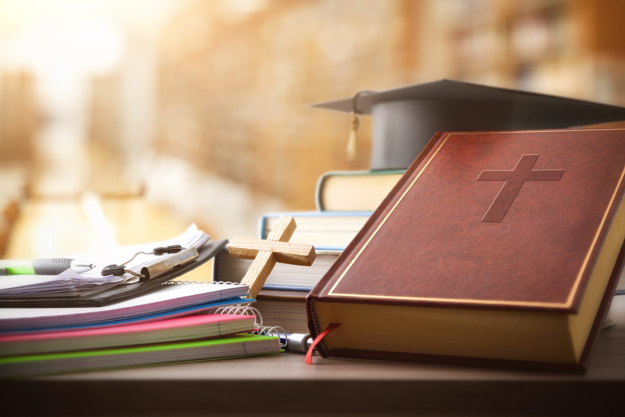 Bible and graduation cap on desk