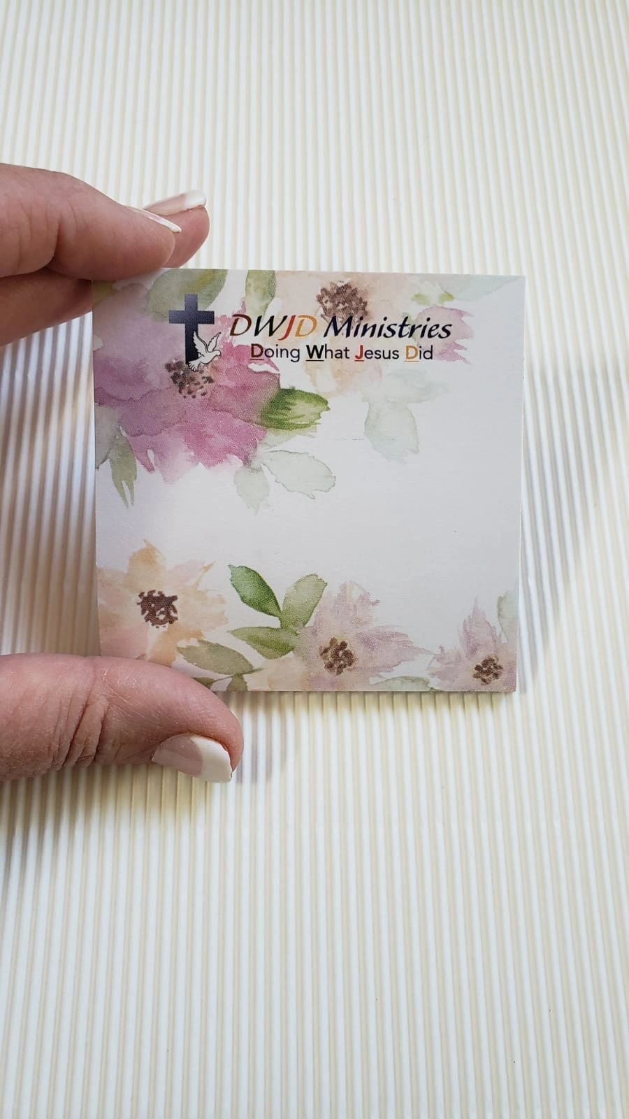 Person holding decorative note card with flowers.